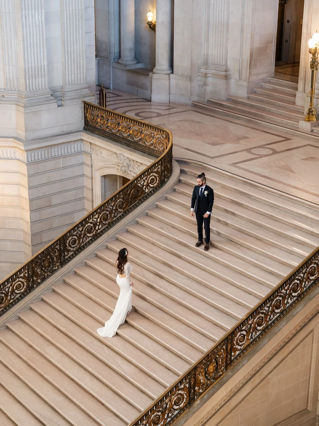 Bride walks up the sf city hall stairs up to the groom