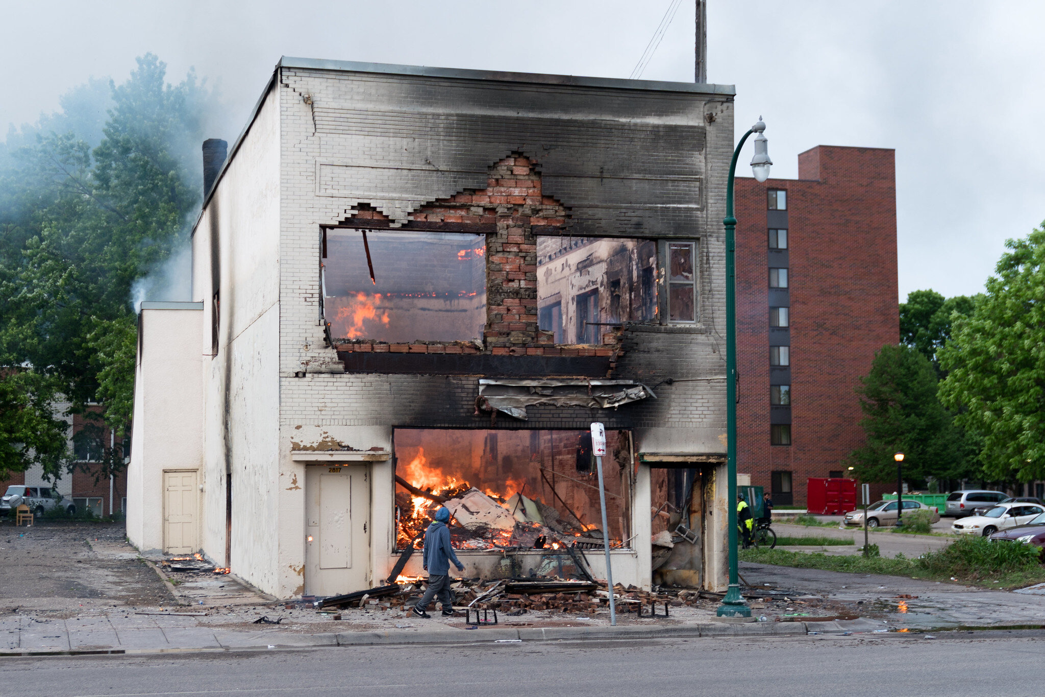 A man walks by a burning building on Thursday morning after a night of protests and rioting in Minneapolis, Minnesota 