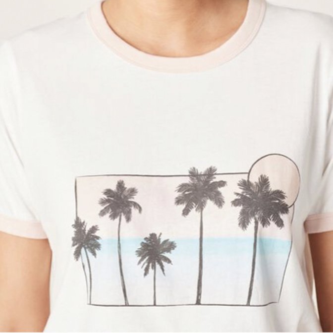 White T-shirt with a design of palm trees and a sun over a horizon line.