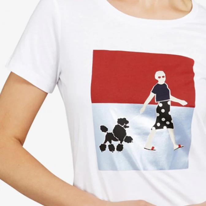 Close-up of a person wearing a white T-shirt with a graphic design featuring a woman walking a poodle. The background of the design has a red and blue striped pattern.