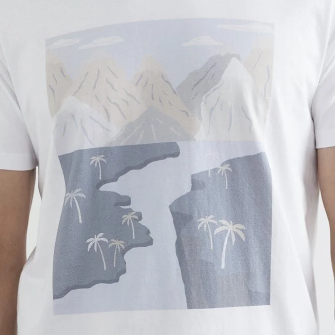 White T-shirt featuring a graphic design of a mountain landscape with a river, palm trees, and a partly cloudy sky.