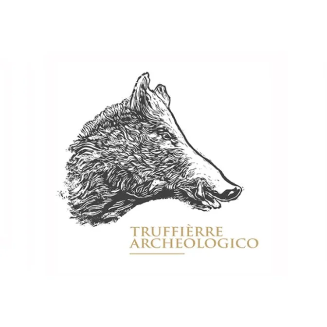 A detailed black and white illustration of a wolf's head in profile facing right, with the words "TRUFFIÈRE ARCHEOLOGICO" written below in gold-colored text.