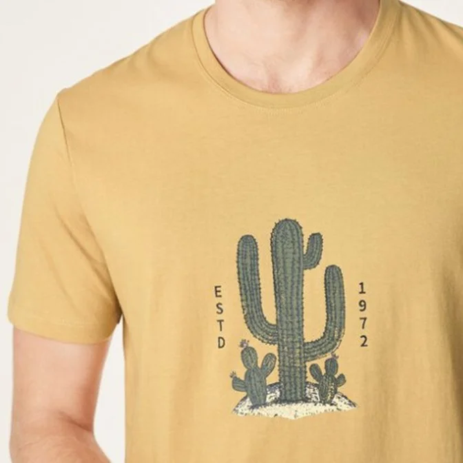 Close-up of a yellow T-shirt with green cactus illustrations and the text "ESTD 1972".