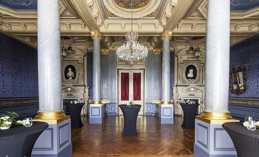 Salle élégante avec des colonnes ornées et un lustre.