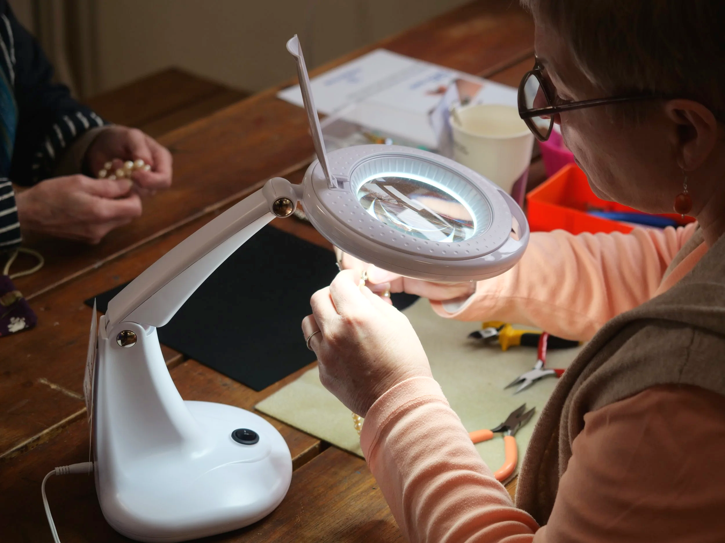 Repairer fixing jewelry under magnifying glass.