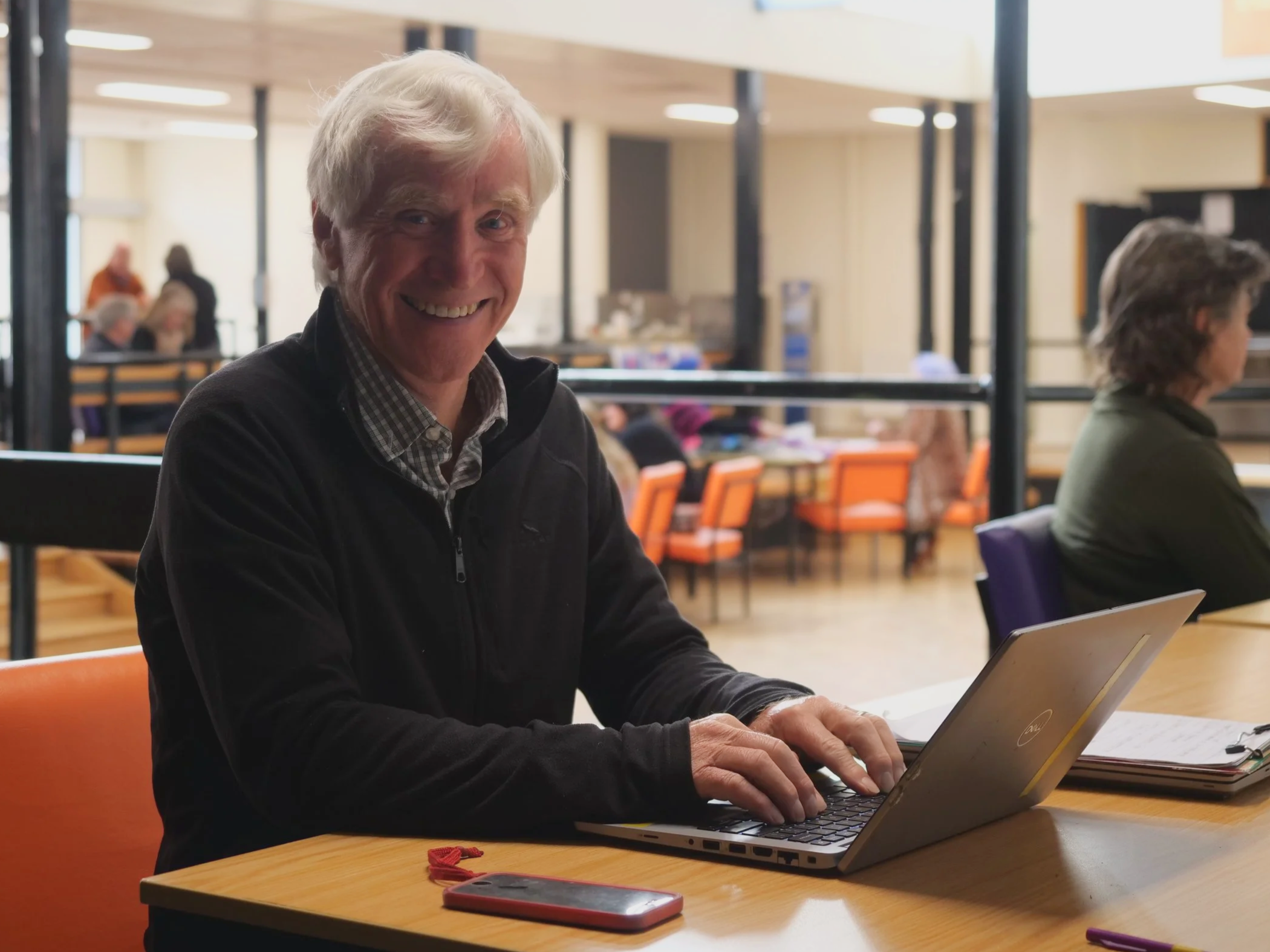 Man smiling behind laptop.