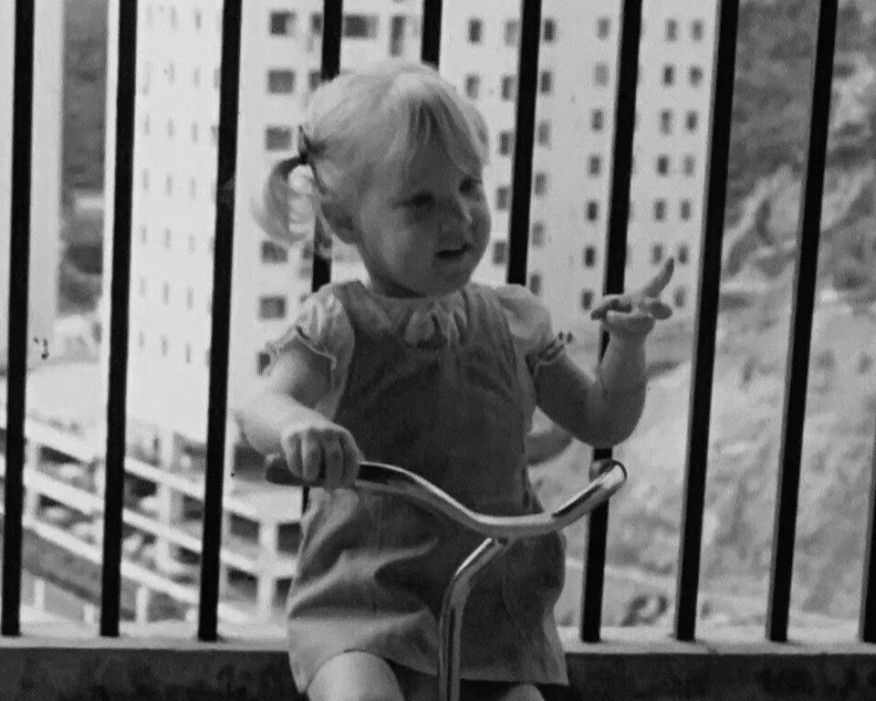 Black and white photo of baby Lucy riding her trike