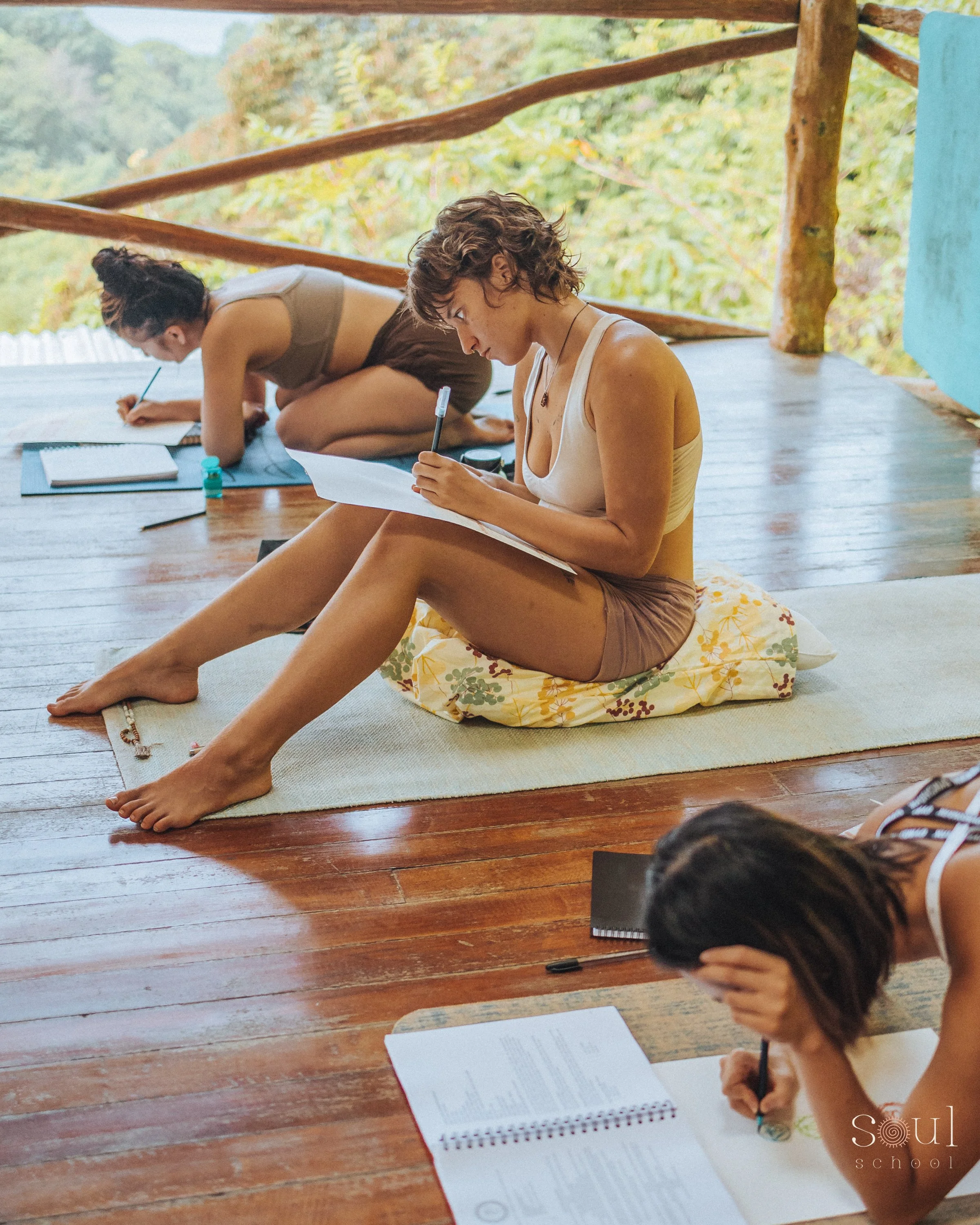 Students journaling during a Spirit Alchemy yoga teacher training retreat in an open-air jungle studio.