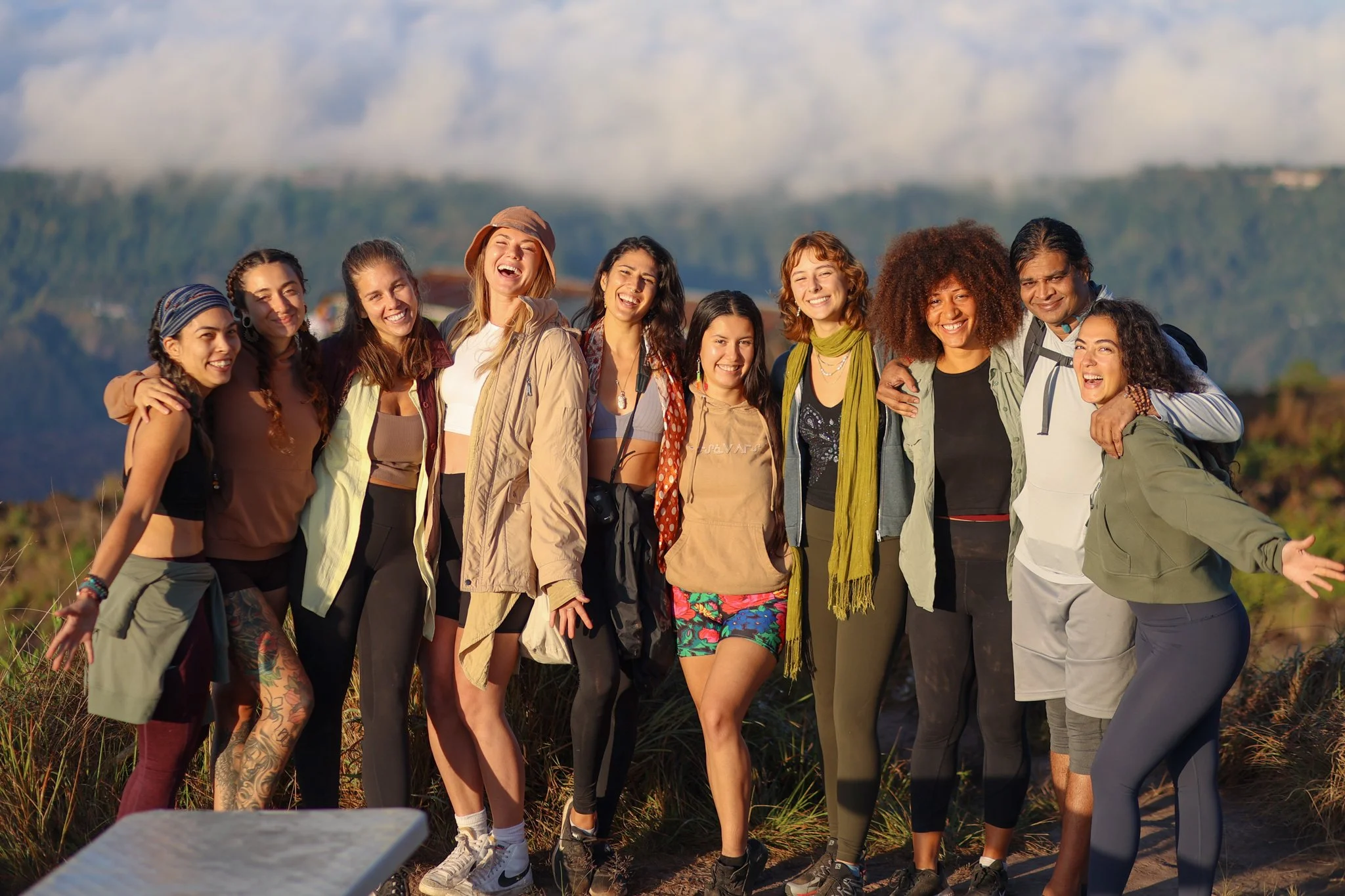 Group of diverse friends on a hike, standing together outdoors with mountains in the background, smiling and having fun.