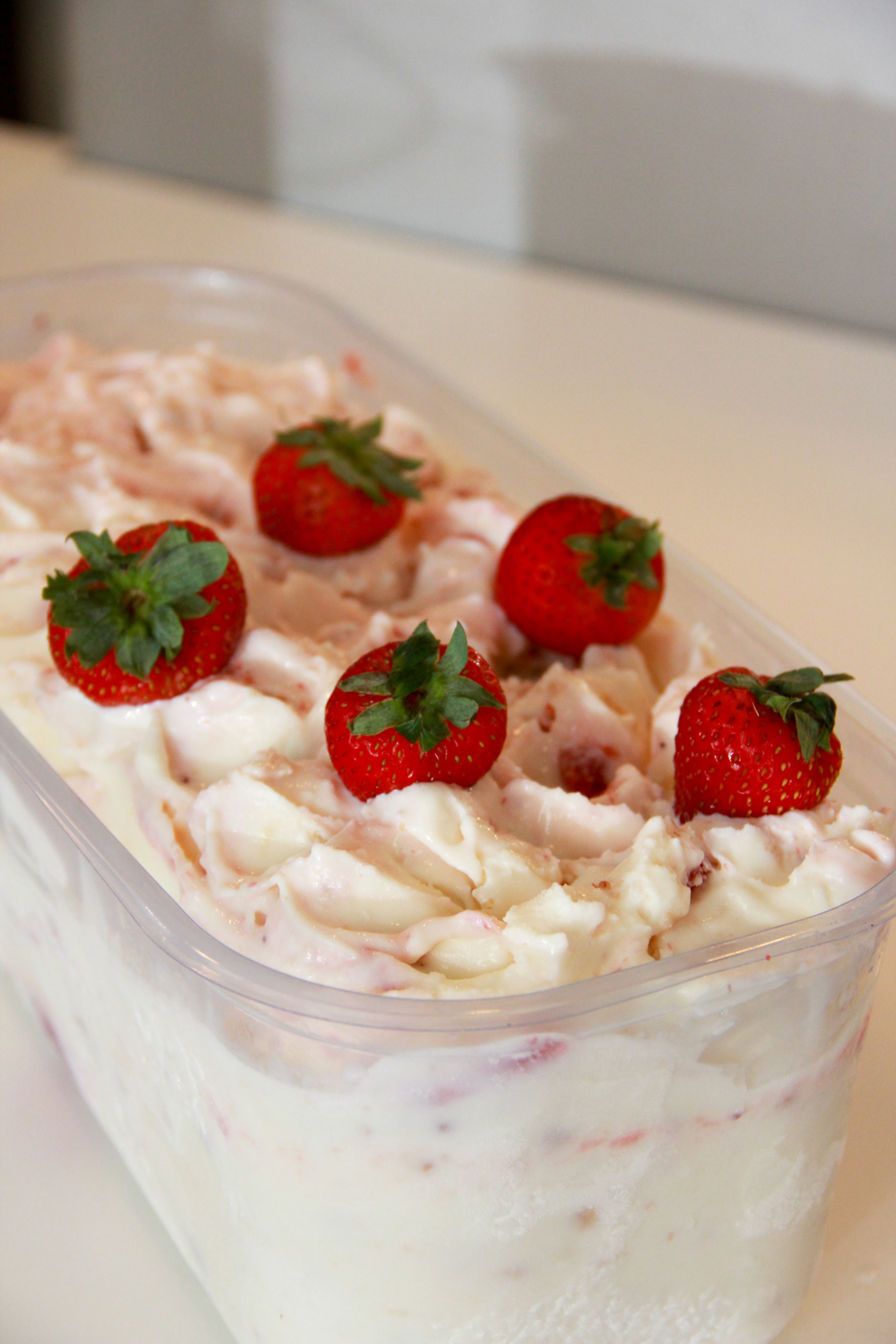 A tray of gelato topped with fresh strawberries.