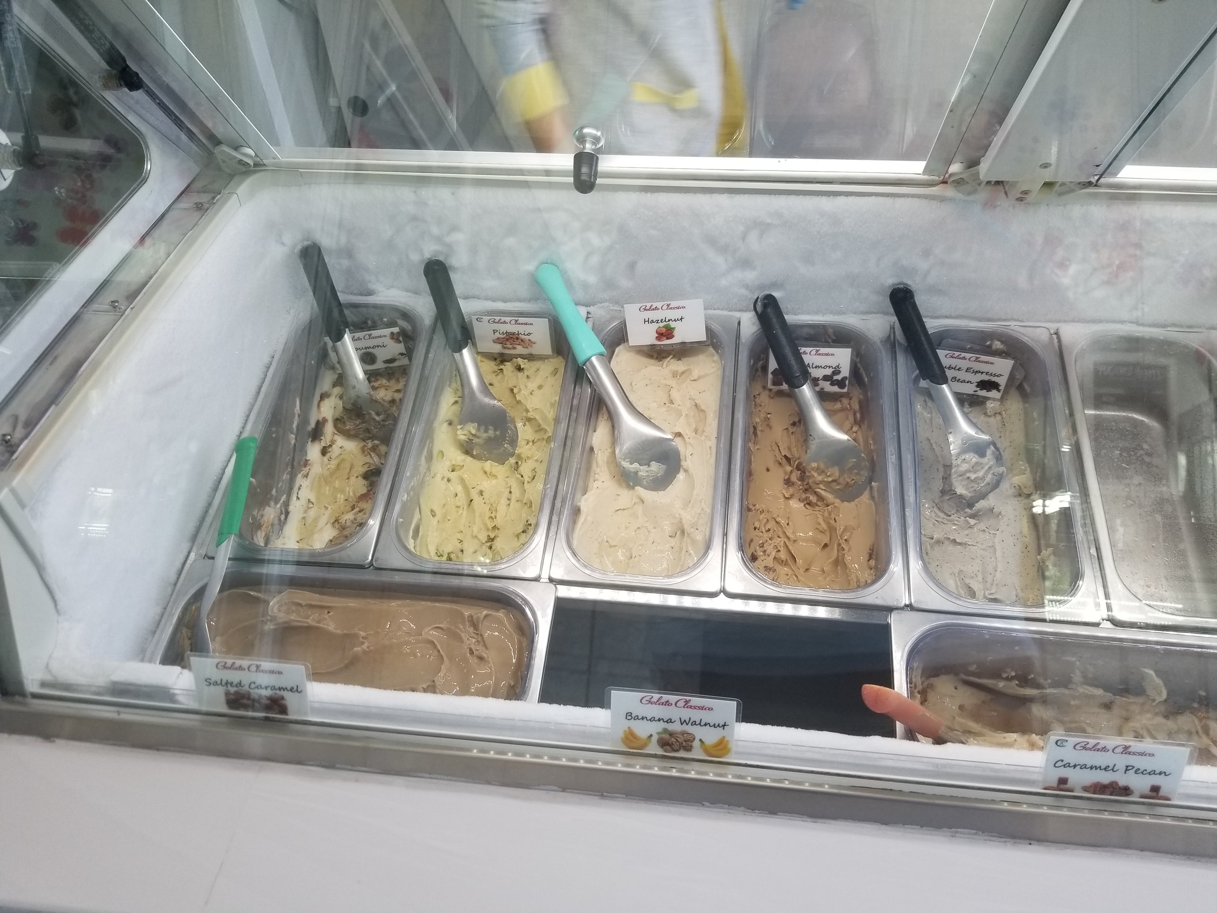 A freezer case filled with scoopable gelato in multiple flavors.