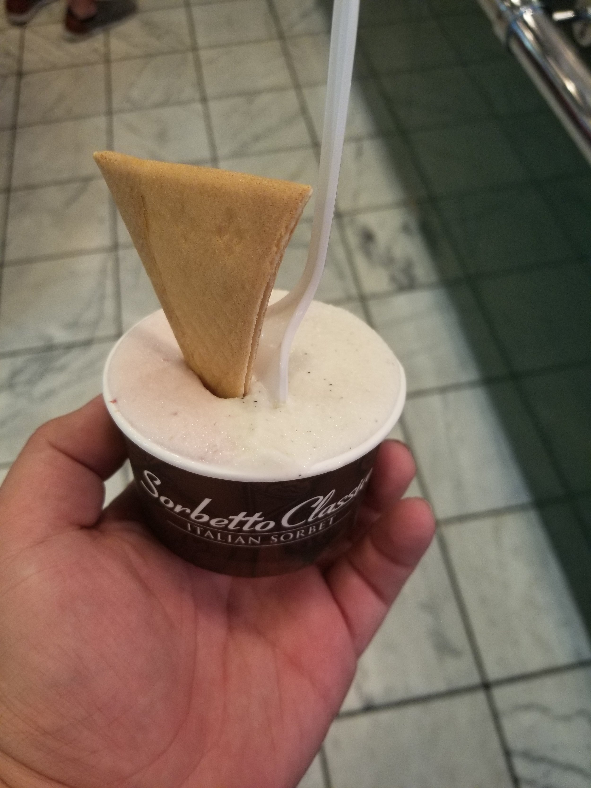 A cup of gelato topped with a triangular wafer cookie.