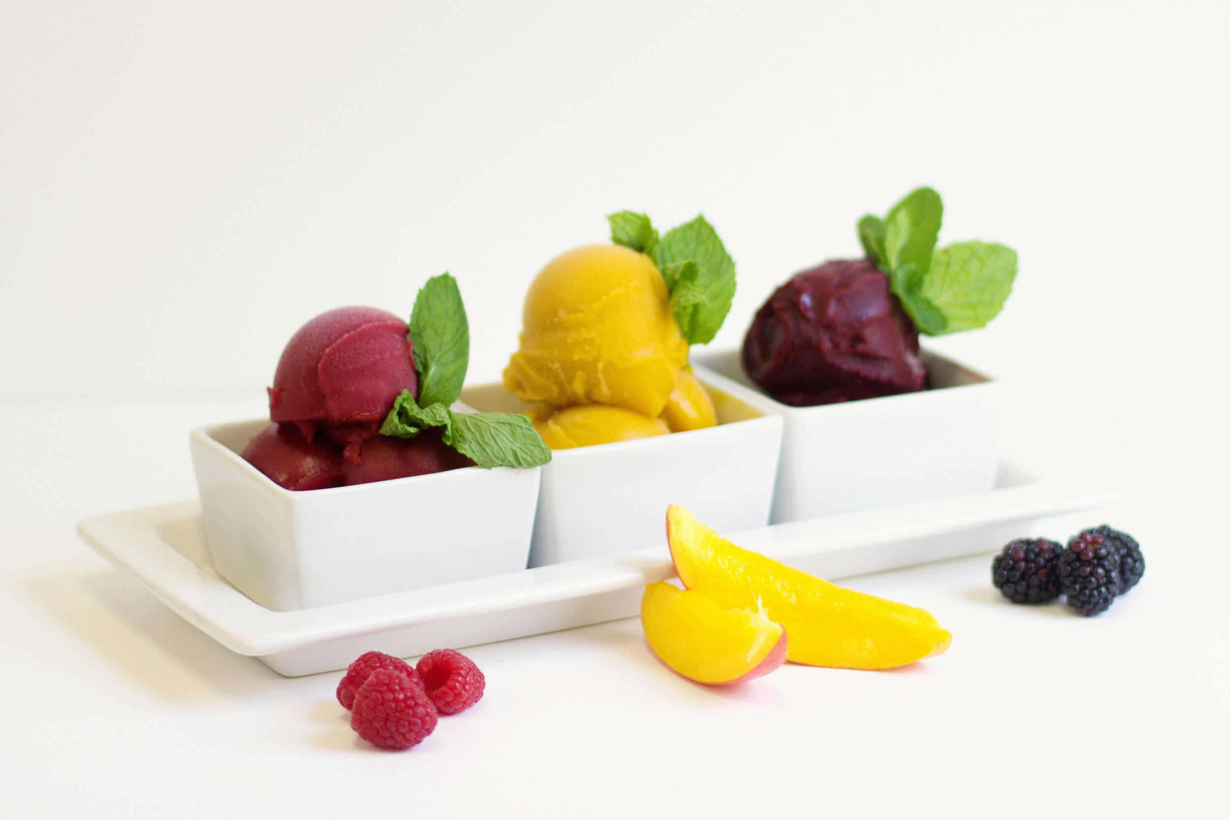 Three types of sorbet in square white bowls.