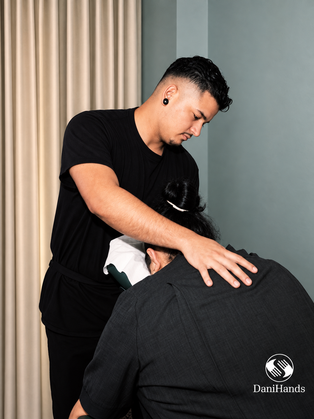 Massage therapist providing a massage to a client with their head resting on a pillow in a professional setting.