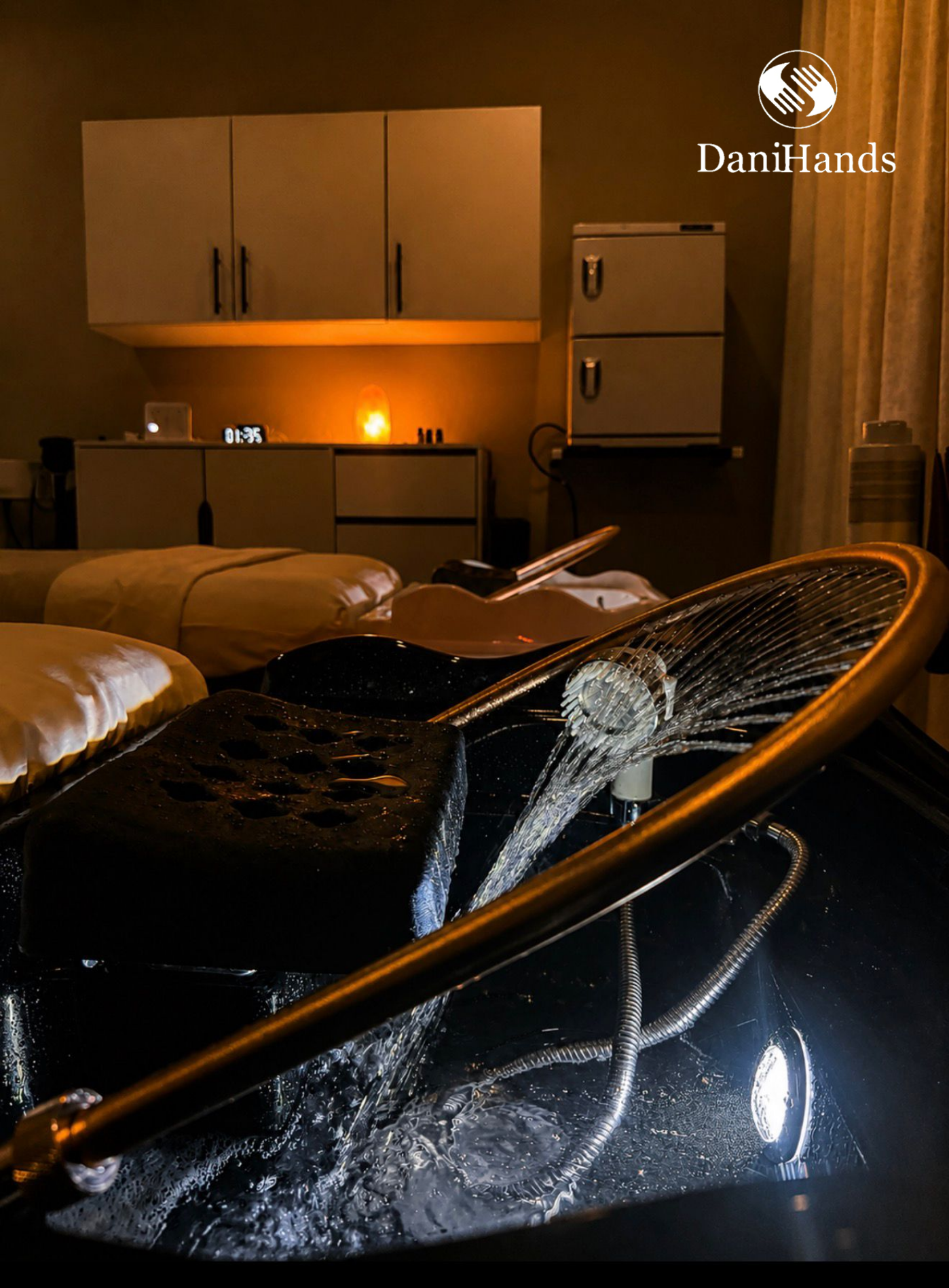 A black chair with water pouring over it from a fountain or water feature in a dimly lit room with a bed and cabinets in the background.