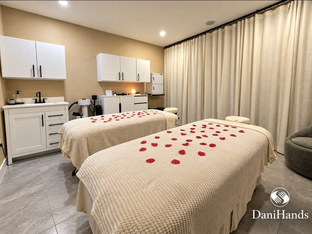 Spa treatment room with two massage beds covered in beige blankets and scattered red rose petals.