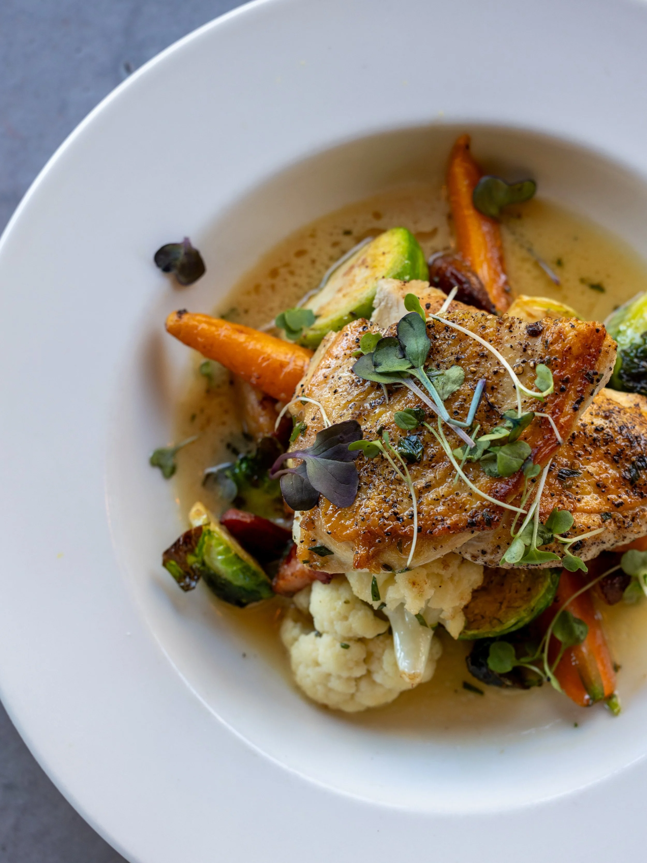 Golden brown Mary&rsquo;s Chicken Breast with Brussels sprouts, bacon, Nantes carrots, cauliflower, and a Dijon-tarragon pan sauce. The kind of dinner that feels like comfort food.