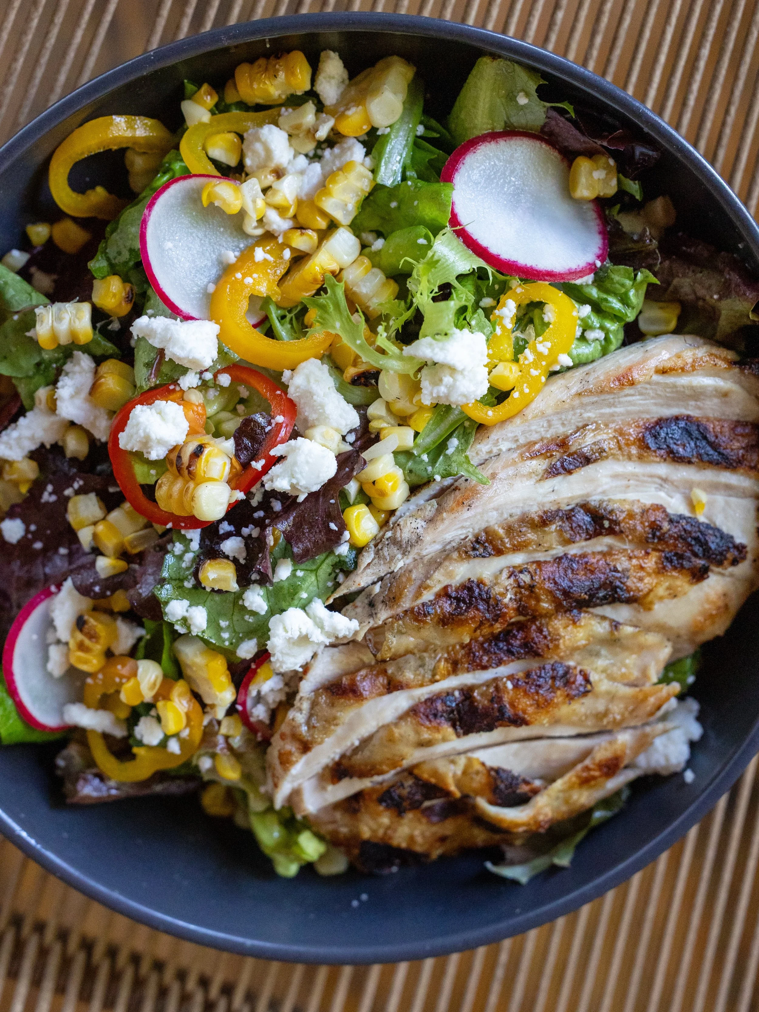 Ensalada de pollo- mixed greens, gem lettuce, jalapeno vinaigrette, Roasted corn, pickled sweet peppers, avocado, pepitas, queso fresco, grilled chicken breast.