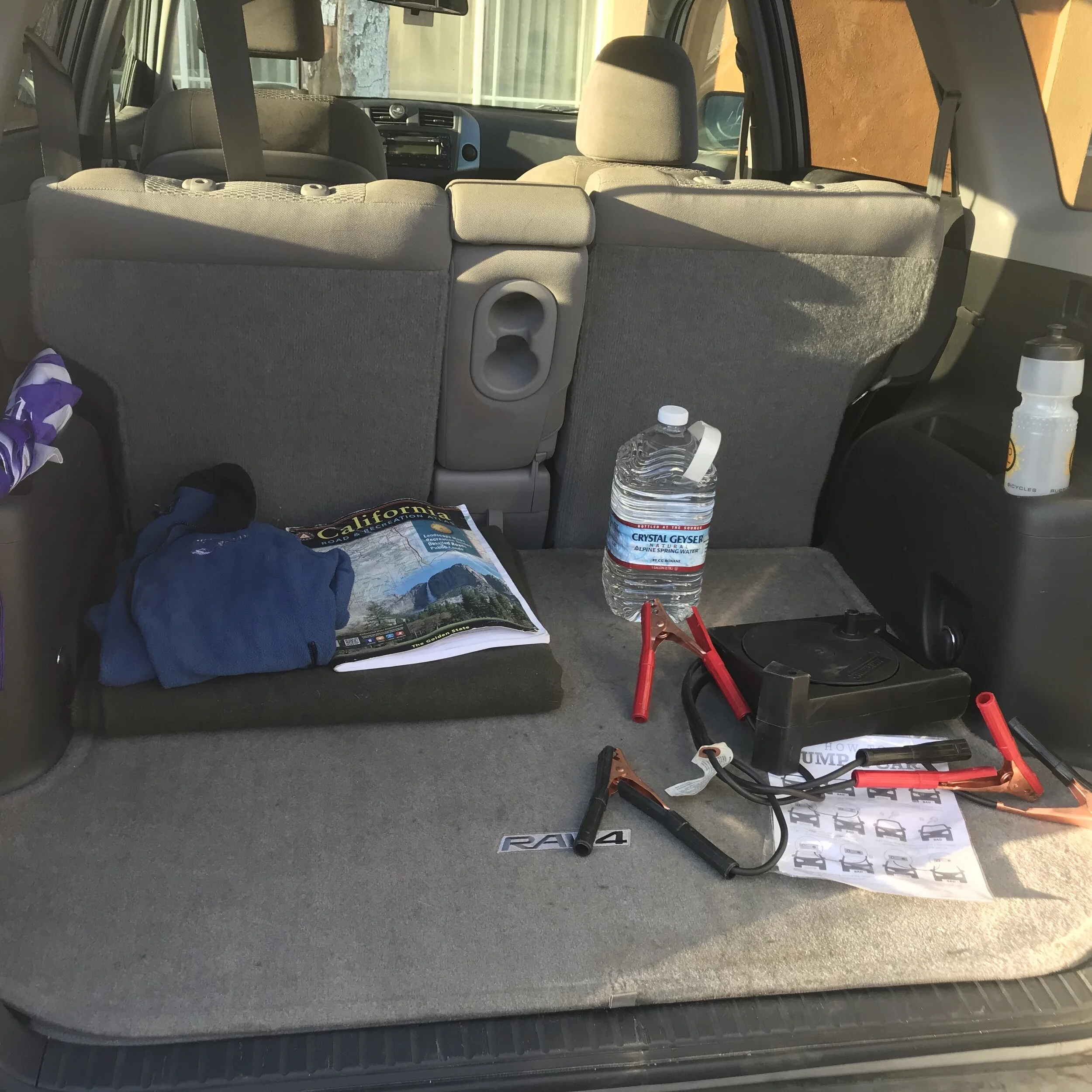 Wool blanket, fleece jacket, state maps, umbrella, water, & jumper cables with instructions
