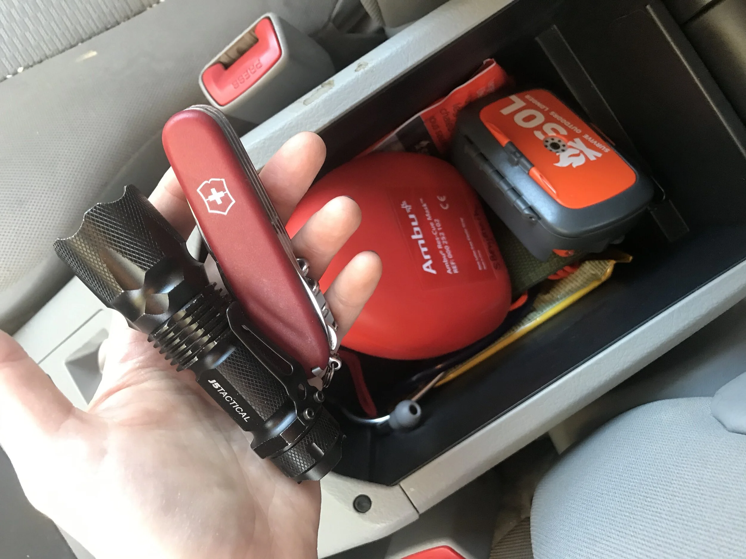 A variety of items live in my middle console, including a tactical flashlight, multi-tools, face mask, outdoor survival kit, reflective space blanket (the kind they give runners after marathons), stethoscope, wet wipes, and more.