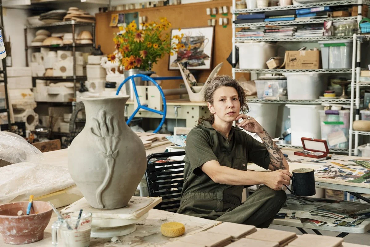 Nicole Helen Brunner sitting in her very full Mountaindale Art Studio