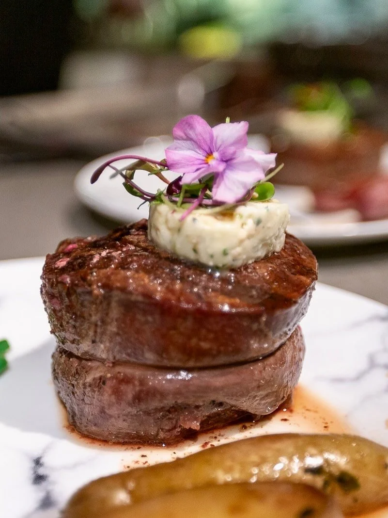 our perfectly seared Filet Mignon, finished with herb butter and garnished with edible florals 🌸&mdash;a show-stopping centerpiece to any fine dining experience.

Dive into the full story behind our Tuxedo Menu and explore more chef-curated selectio