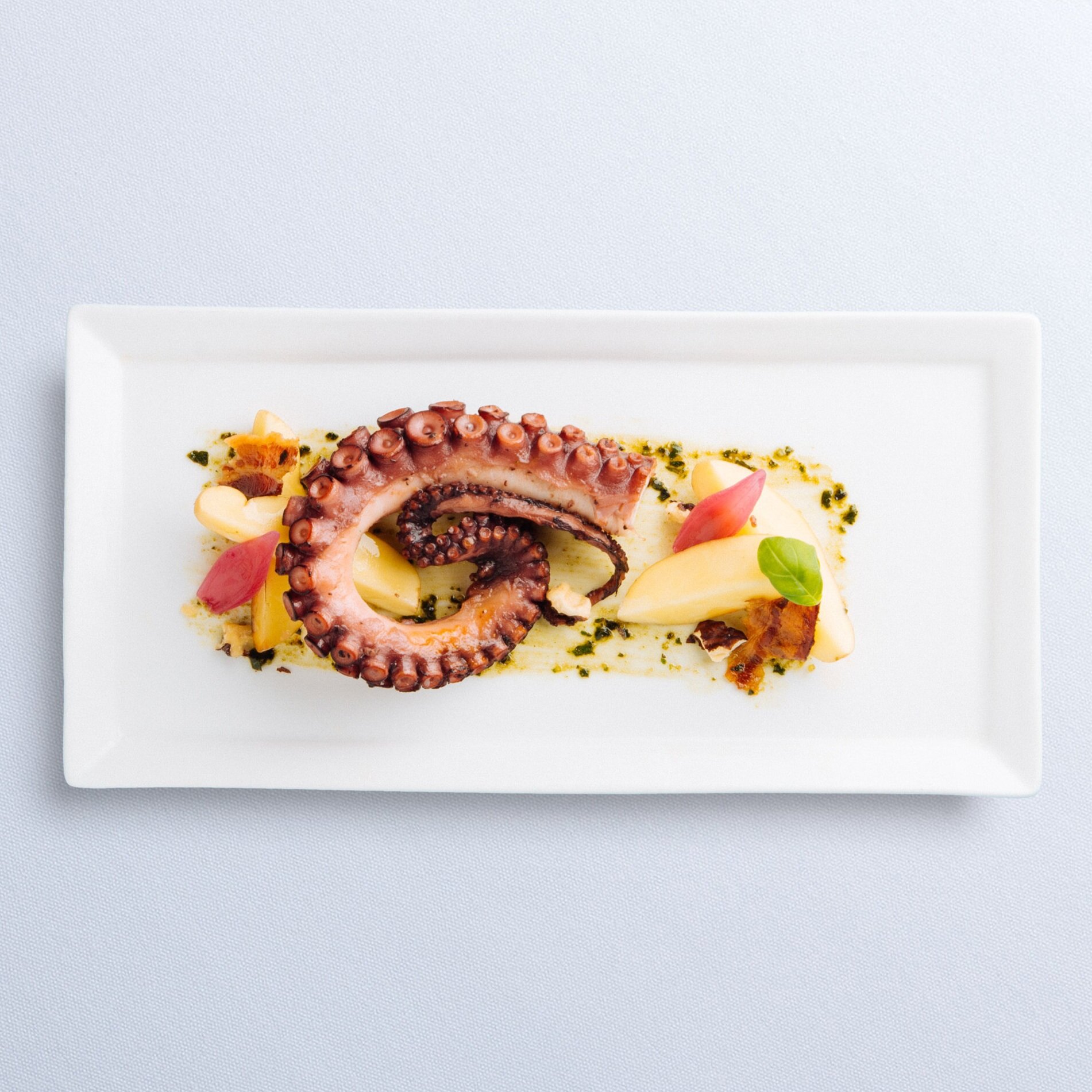 An entrée at The Restaurant of Grilled Octopus, Fingerling Potatoes, Almonds, Prosciutto &amp; Pesto (Copy) (Copy)