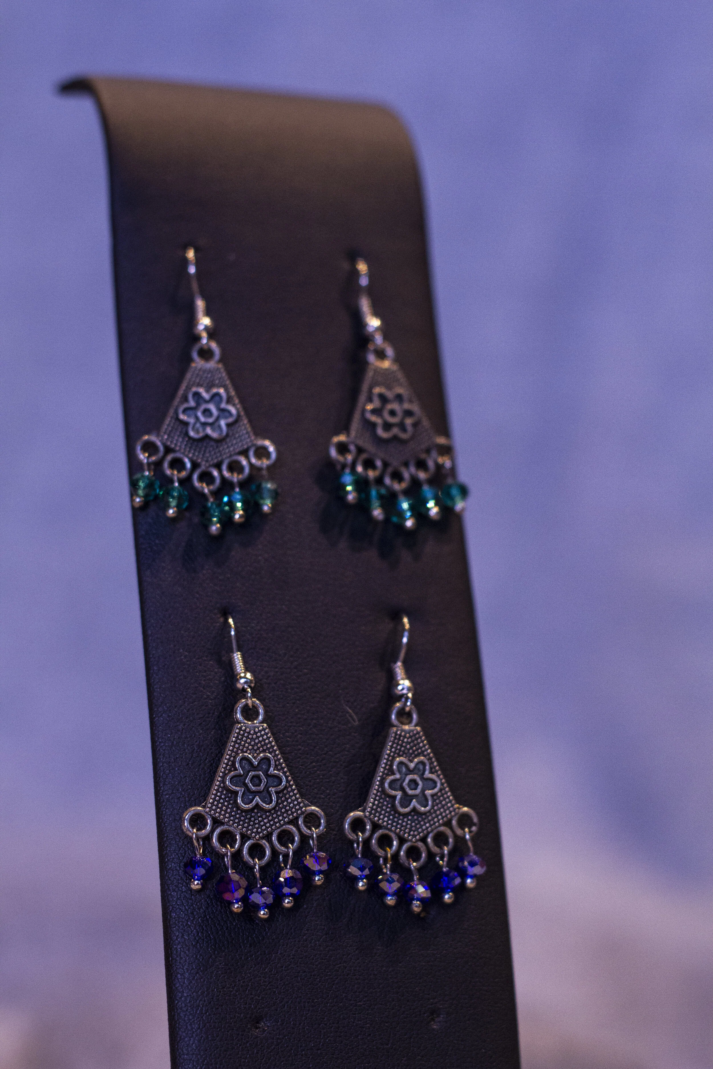 long earrings with a flower hanging on the pendant with green and blue beads hanging off