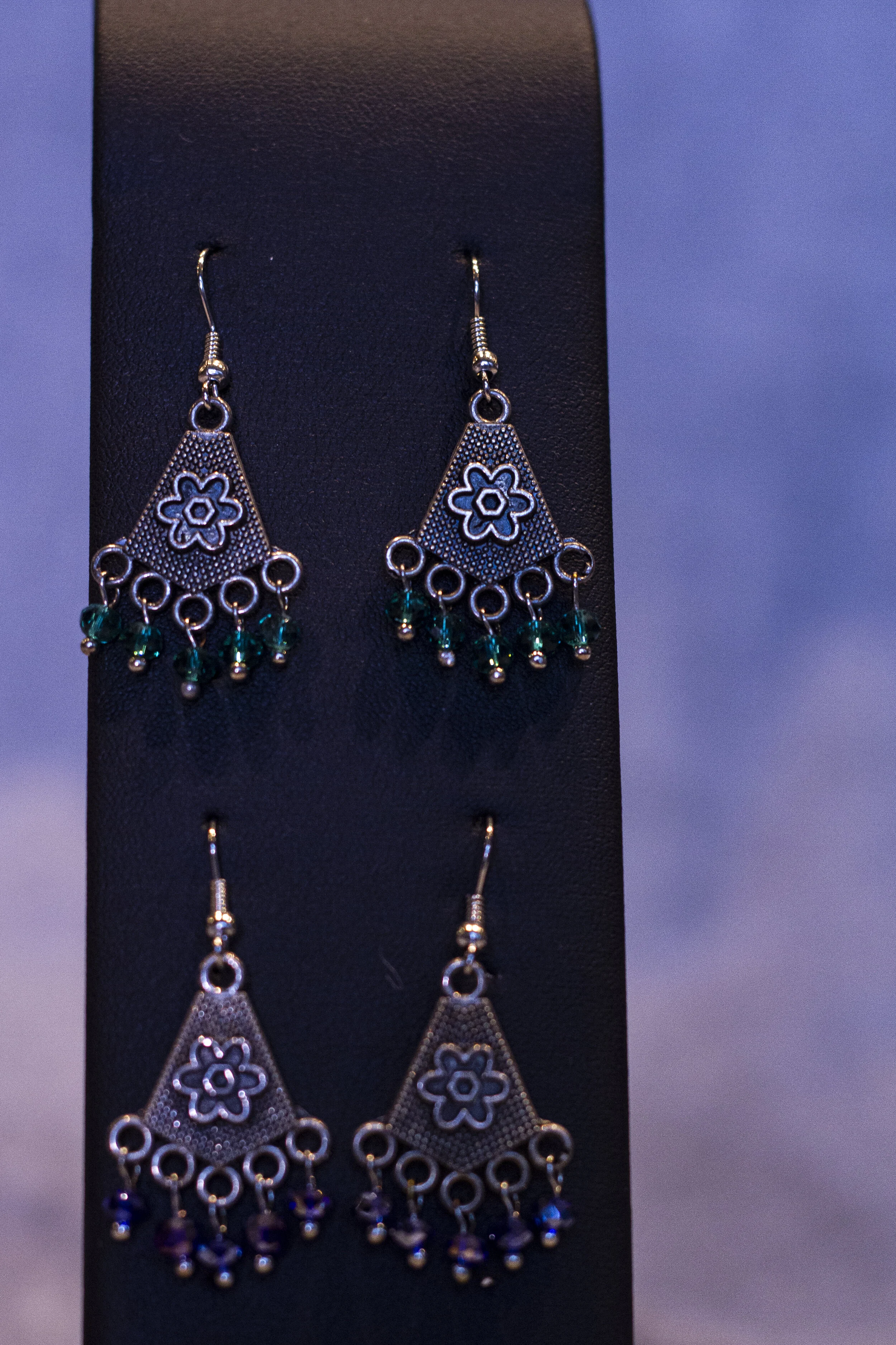 long earrings with a flower hanging on the pendant with green and blue beads hanging of