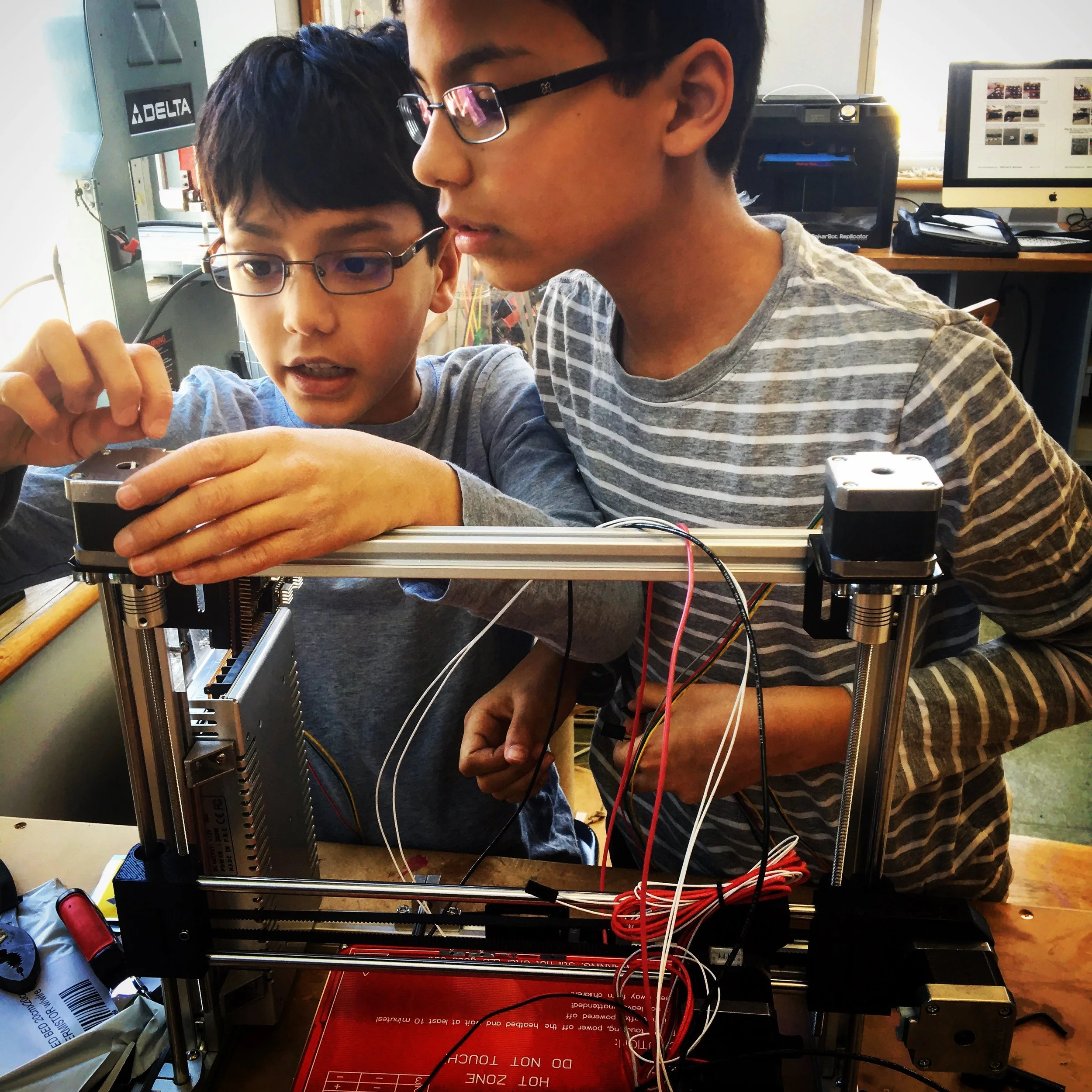 Two young boys work together on an electronics project
