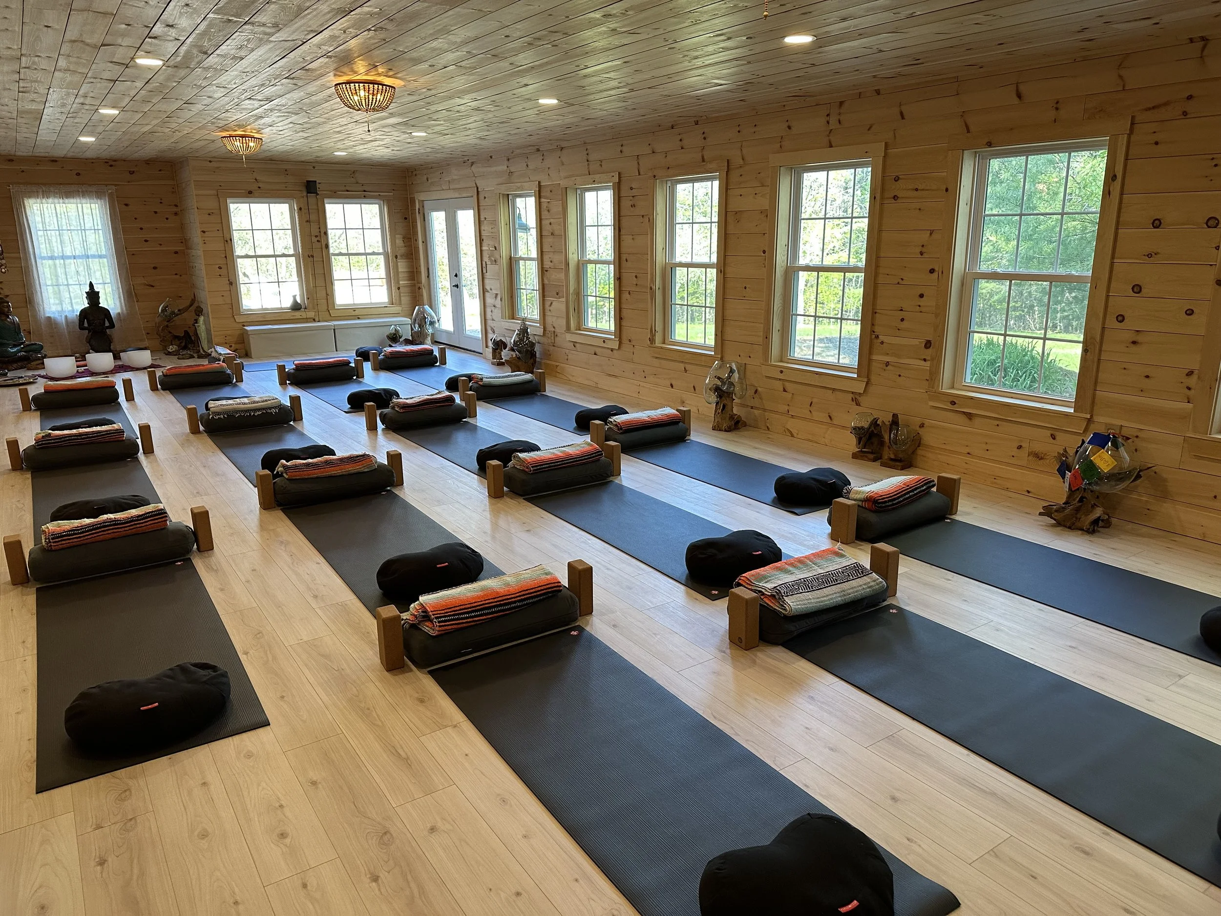 A yoga studio is set up with mats, pillows, and blankets for a class