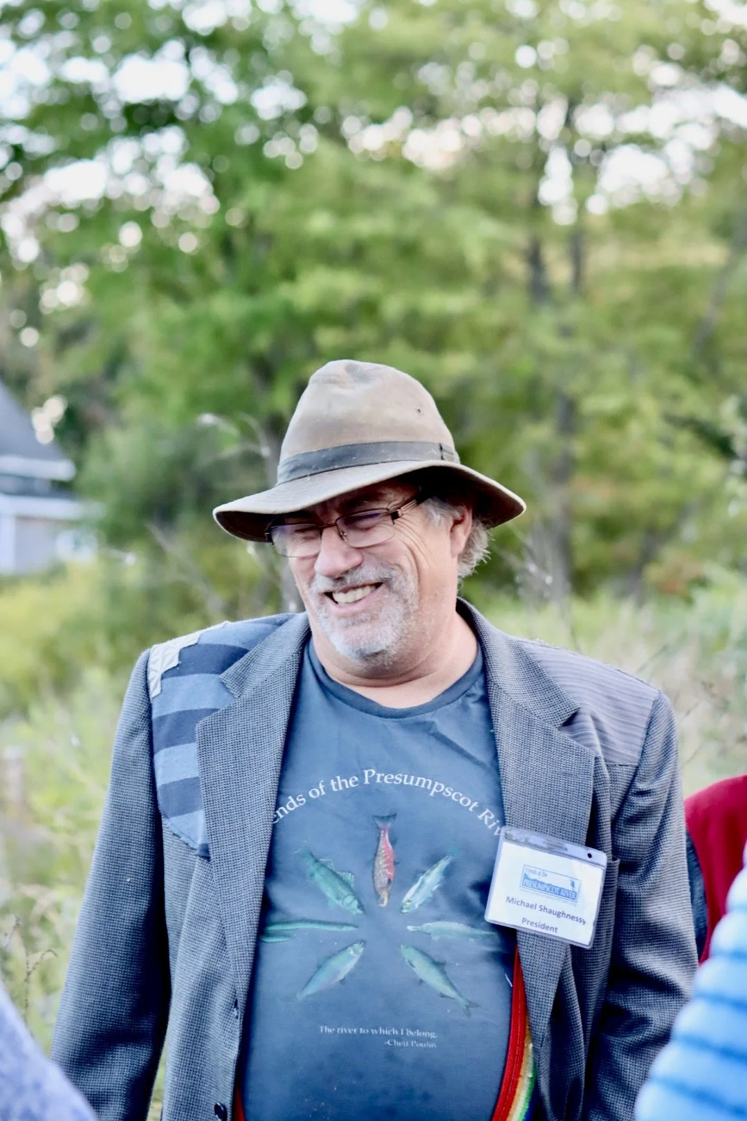 Portrait of Michael Shaughnessy smiling with trees and wildflowers in the background