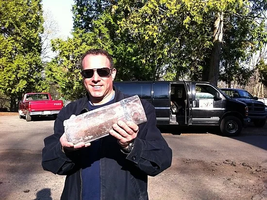Time Capsule Reveals “Grapeshot” When the barrel came up last fall—along with old skulls and bones—local historian Rob Greenberg (pictured holding a capsule) began to suspect it contained a time capsule. He eventually got the city bomb squad to X-ray the concrete lump , revealing enough evidence that Bellantoni and others worked to scan the concrete further, and crack it open to find the capsules. At the press conference Monday afternoon, Drew Days, a Proprietor of the Green, publicly thanked Greenberg for his dogged pursuit of his time-capsule theory, which “kept us focused” on the possibility. ( He barred Greenberg earlier in the day from watching the capsules being opened.) Read the article in the New Haven Independent Time Capsule Reveals “Grapeshot”