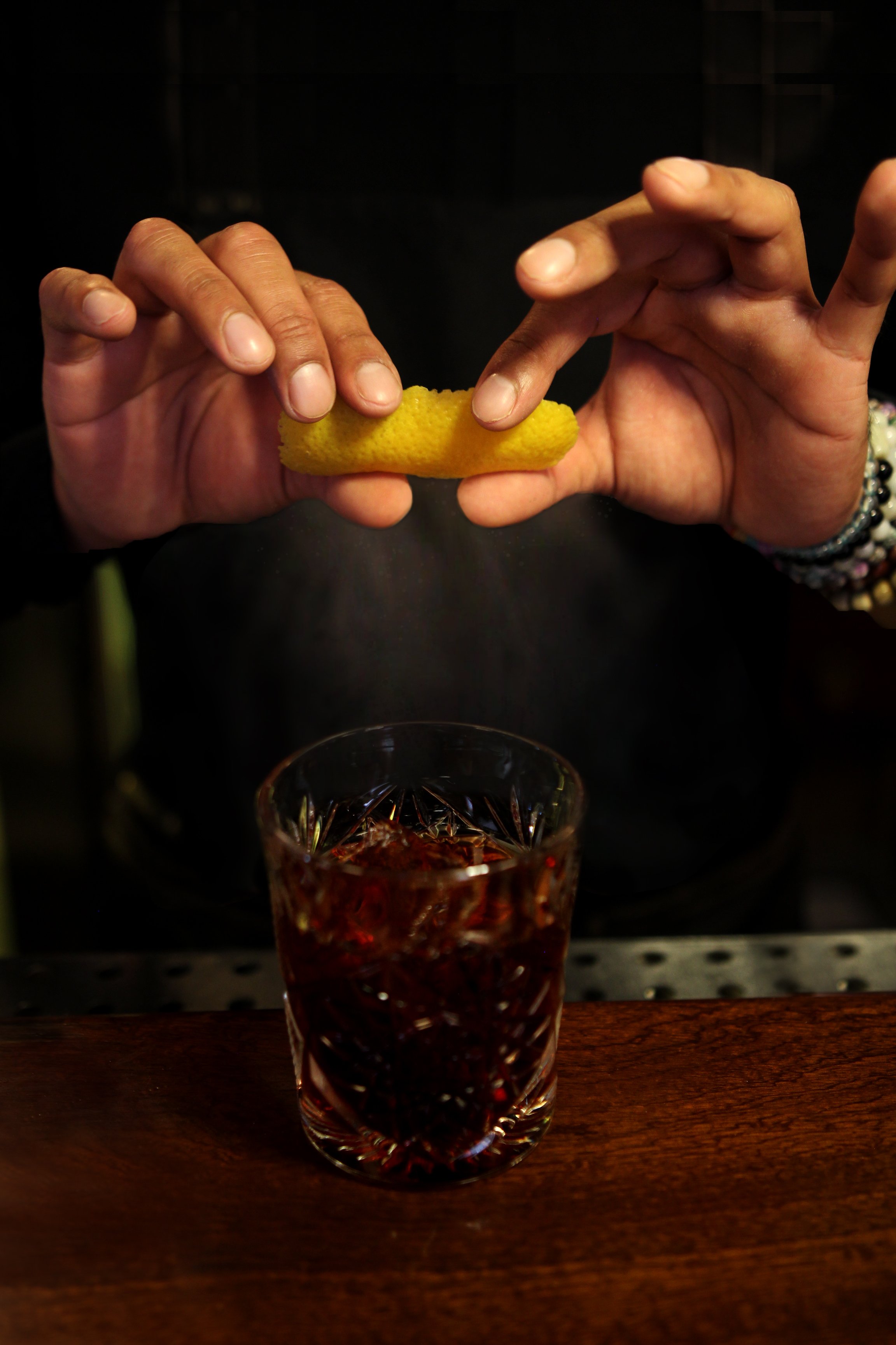 Image of bartender squeezing lemon over cocktail