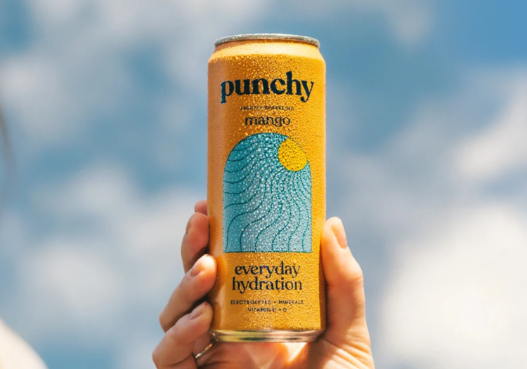  Hand holding a Punchy mango sparkling water can against a bright blue sky, featuring vibrant orange design with hydration benefits and electrolytes. 
