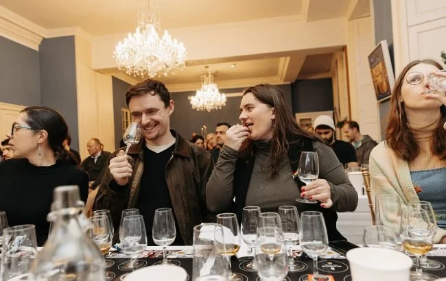  EU Spirits × The Spirits Business × Kristianne Westray tasting event featuring an elegant table setup with multiple spirit glasses under crystal chandeliers in a sophisticated venue. 
