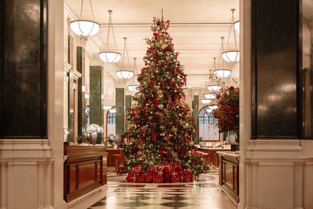  The Macallan reimagined The Ned as a festive showcase of whisky heritage, featuring a grand Christmas tree adorned with red and gold decorations, elegant marble columns, and luxurious holiday ambiance. 