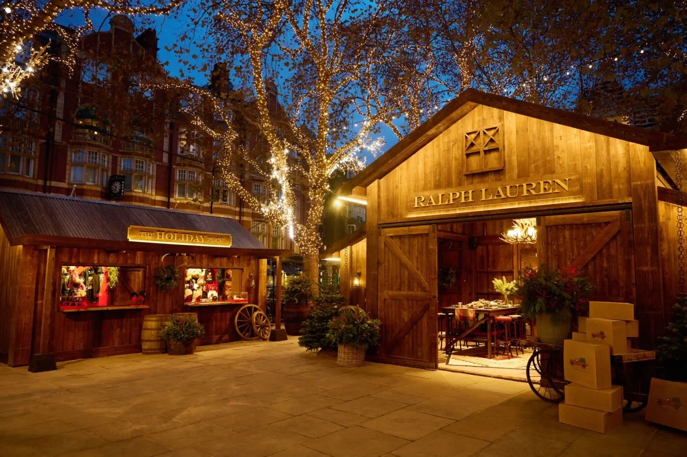  Ralph Lauren Chelsea Holiday Pop‑Up featuring rustic wooden cabins adorned with festive décor, twinkling lights on trees, and elegant seasonal displays creating a luxurious winter shopping experience. 