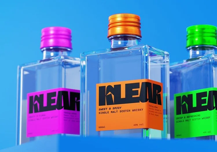  Colorful Klear single malt whisky bottles with vibrant labels and metallic caps displayed against a bright blue background. 