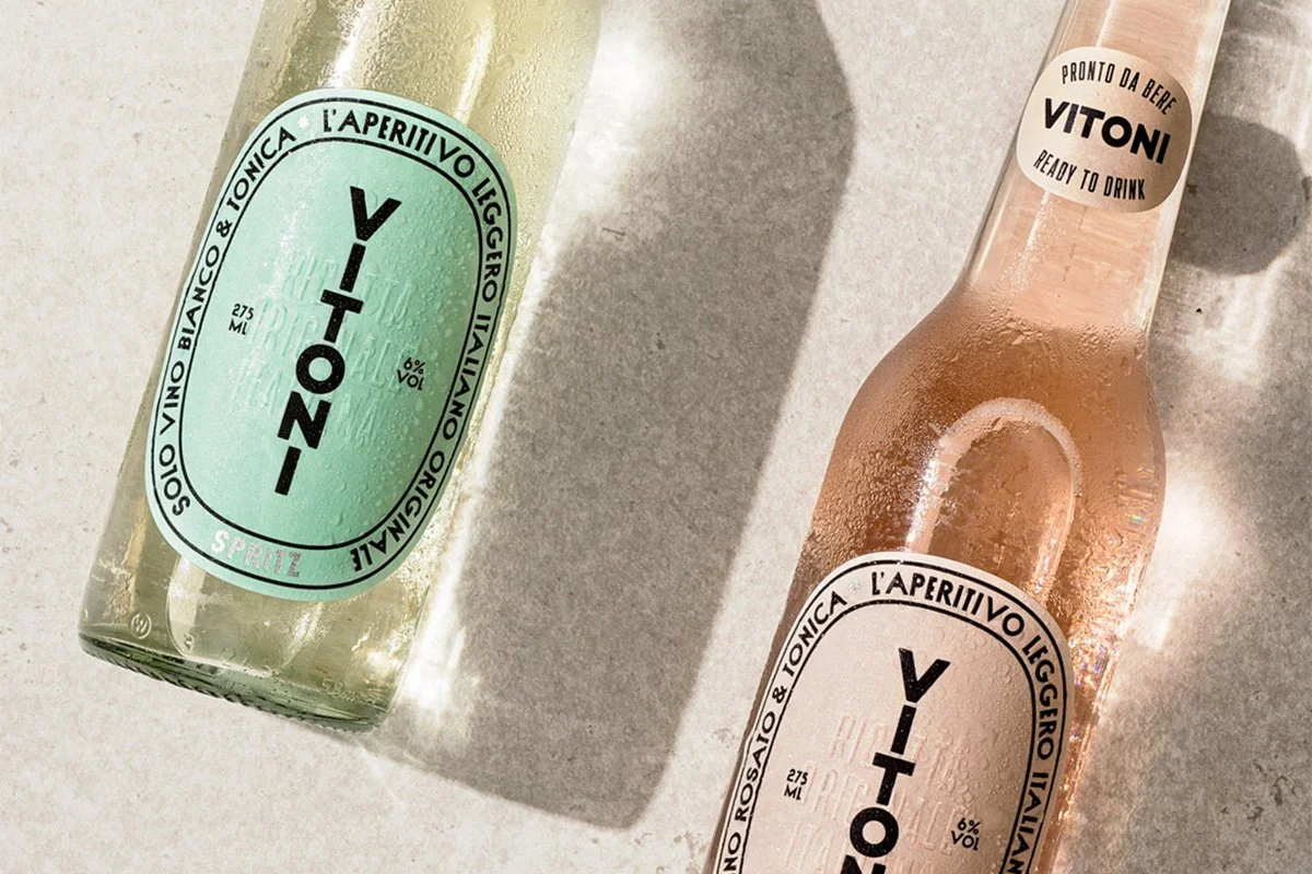  Two Vitoni Italian aperitivo spritz bottles in bianco and rosato displayed on a sunlit surface, with condensation and minimalist branding highlighting a refreshing ready‑to‑drink spritz serve. 