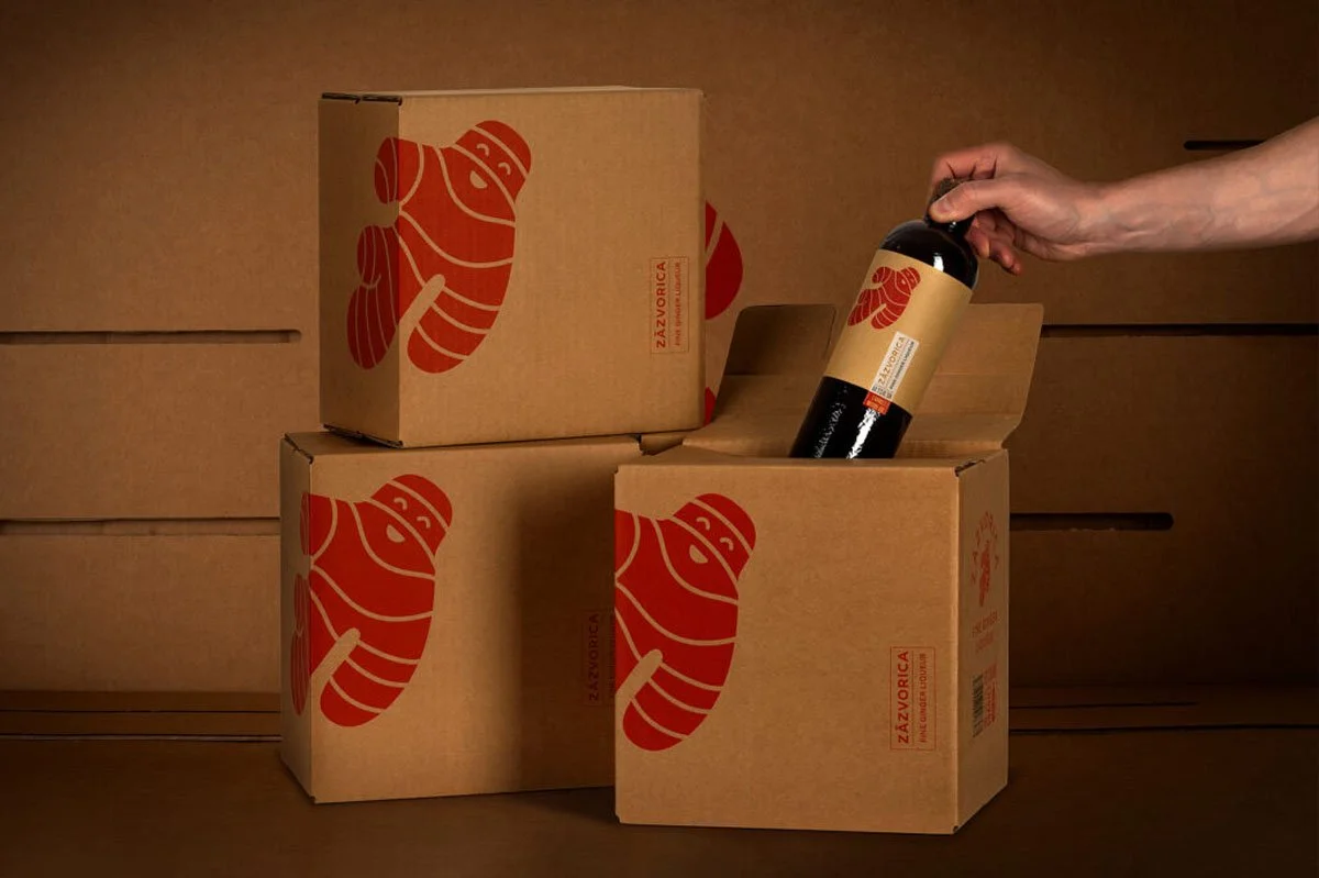  Hand selecting a bottle of Zázvorica ginger liqueur from branded packaging boxes, showcasing distinctive ginger root artwork and premium Slovak craftsmanship rooted in traditional culture and heritage. 