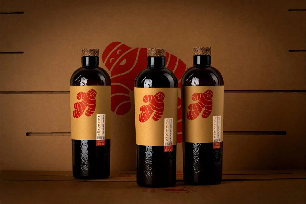 Three bottles of Zázvorica ginger liqueur displayed against a warm brown backdrop, featuring distinctive ginger root illustrations on the labels, highlighting a premium Slovak spirit deeply rooted in Slovak culture and tradition.