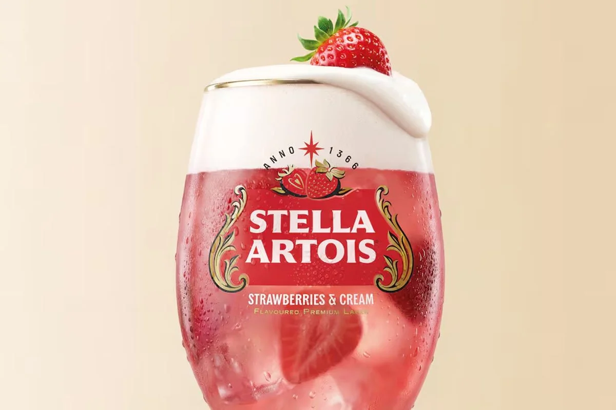 Stella Artois Strawberries & Cream campaign visual featuring a pink fruit‑flavoured lager served in a branded chalice glass, topped with cream and a fresh strawberry, inspired by Wimbledon’s iconic summer serve.