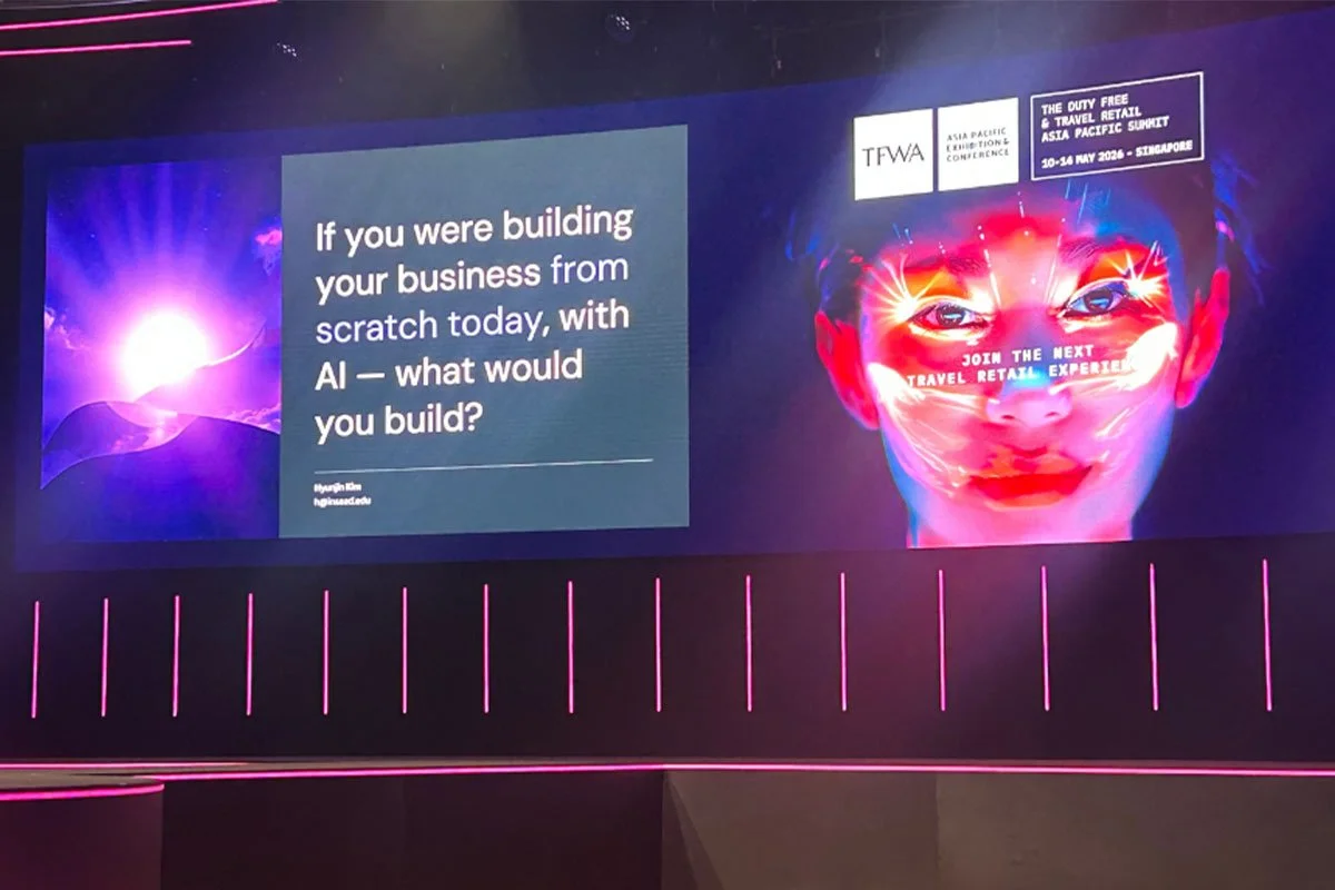 Conference stage at TFWA Asia Pacific 2026 featuring large digital screens with AI and business messaging, alongside vibrant visuals promoting travel retail innovation in Singapore.