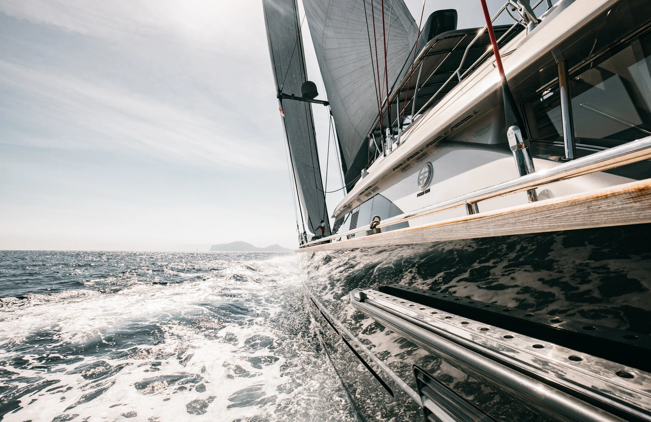 Sailboat cutting through ocean waves, representing DDIMG strategic wealth management and market risk management during volatility