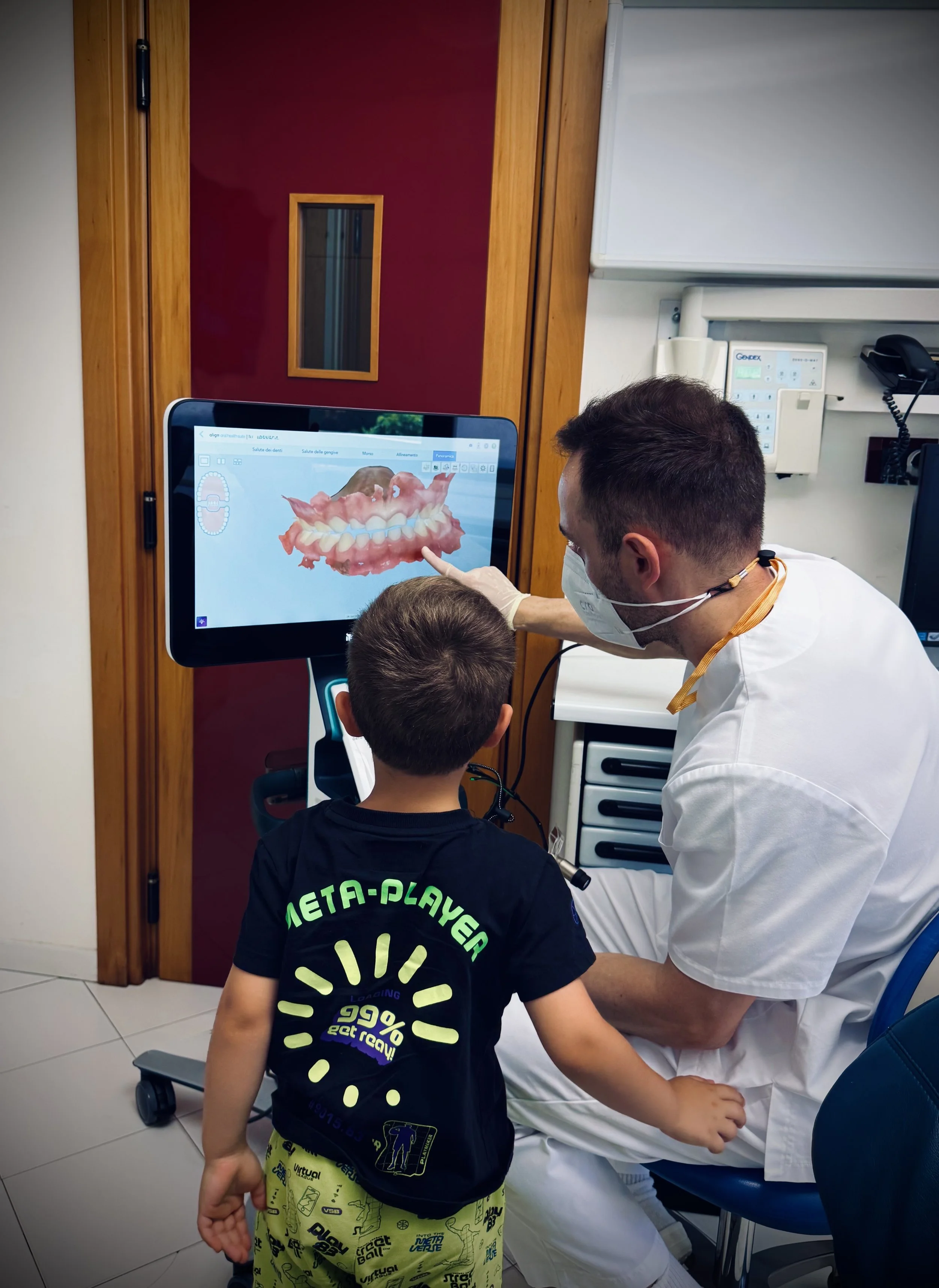 Dentista dello Studio Mattei mostra a un bambino la scansione 3D della sua bocca su un monitor touch, spiegando l'igiene orale in modo divertente grazie allo scanner intraorale.