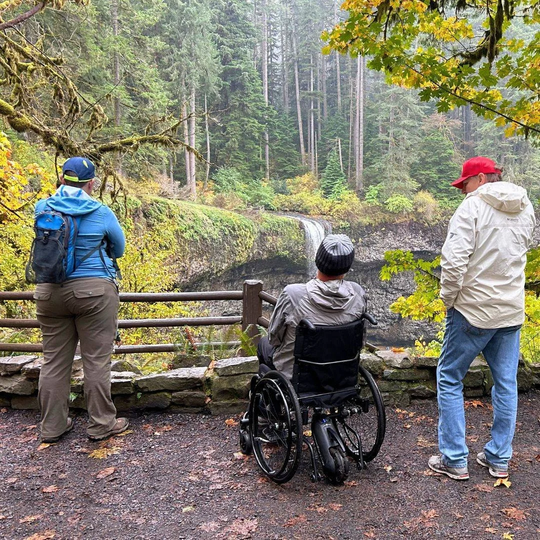 It's the first day of fall! 

What are your favorite fall activities? 🍁🍂

Image Description: A group of three people, one using a wheelchair, look away from the camera towards a waterfall and some colorful fall foliage.