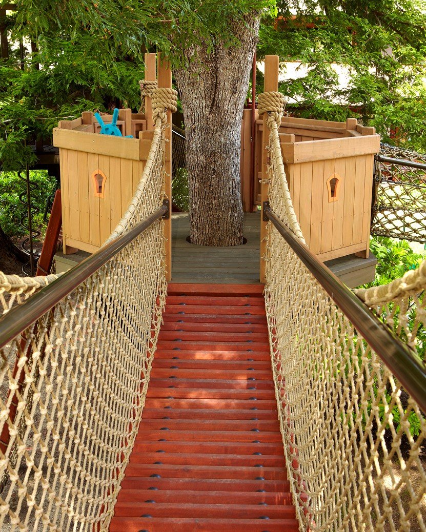Four ways on or off this tree perch guarantees hours of play on this sprawling custom treehouse. Swinging rope bridges provide quick access, a rope crawl tube provides an escape for those willing to test their dexterity and a slanted rope climb provi