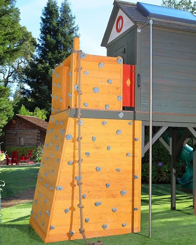 This bright yellow rock wall brings year round cheer and fun to a beautiful yard. Climb up, slide down, the play goes round and round!

#playfort #kidsfort #backyardfort #customplaystructure #playstructure #playhouse #climbingwall #rockclimbing #rock