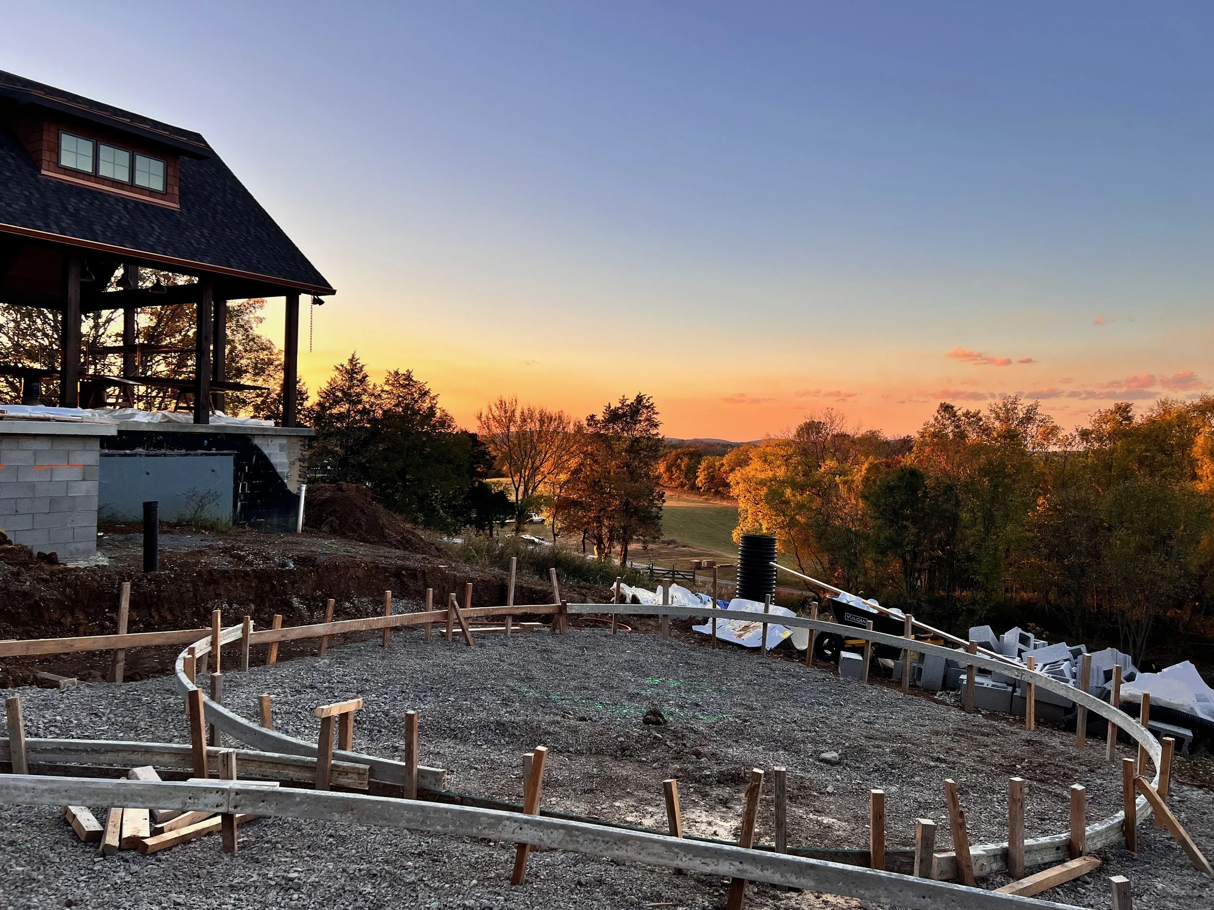 A Middle TN rural estate being built on top of a hill with pond and hardscape construction at sunset.